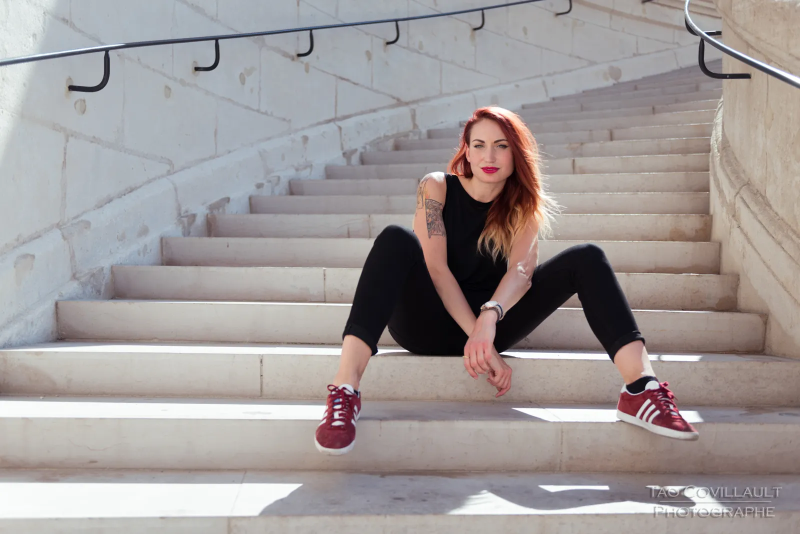 Woman in black clothing posing on pale stone steps.