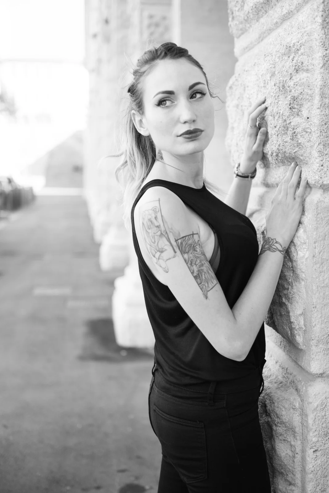 Black-and-white photograph: woman in black clothing posing on pale stone steps.
