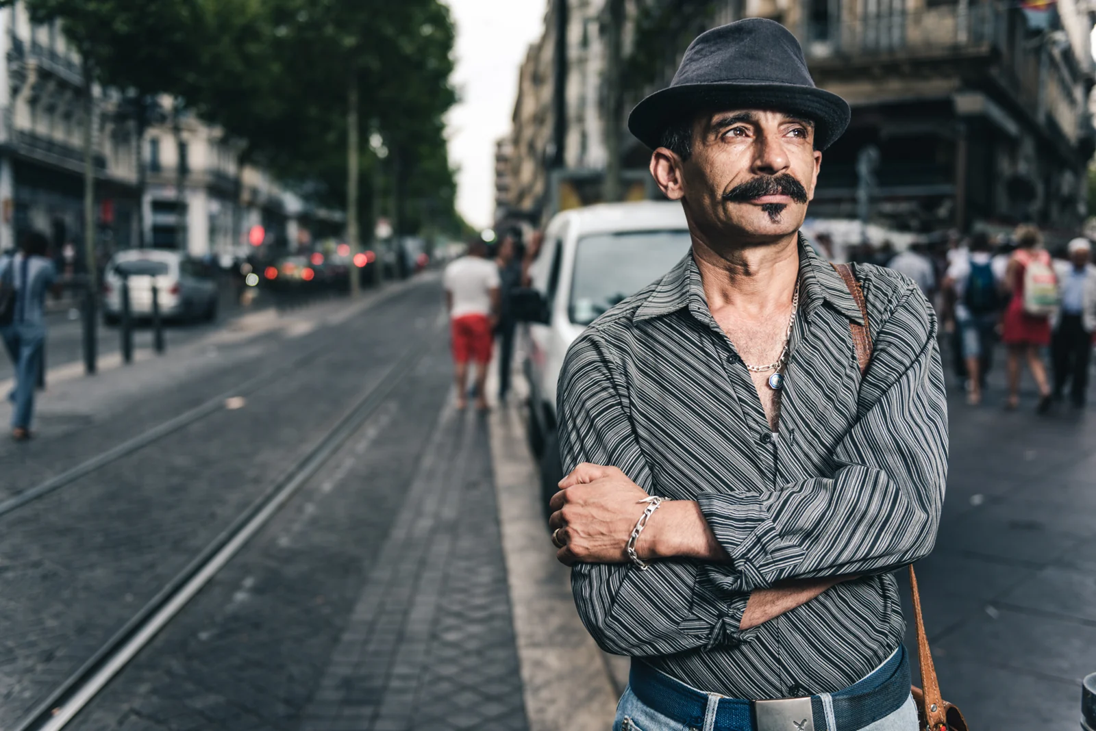 Man wearing a hat standing on a city street.
