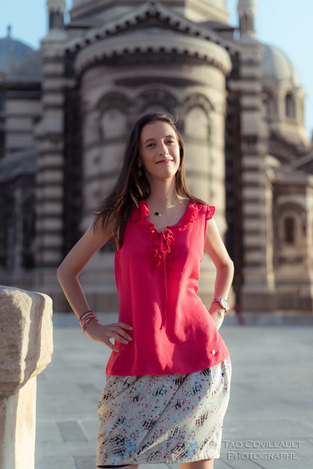 Woman in a bright pink top posing outside an ornate domed stone building.