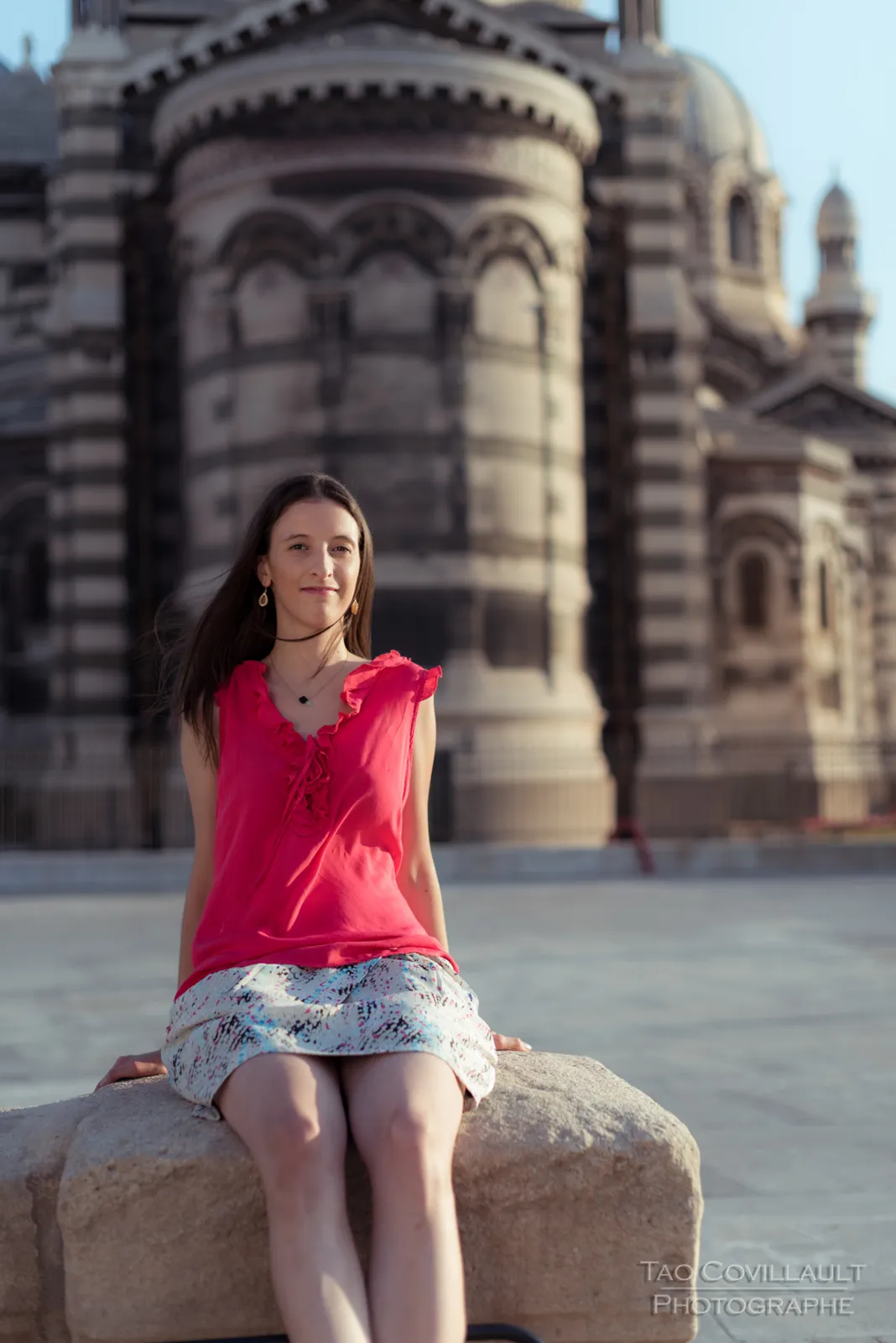 Woman in a bright pink top posing outside an ornate domed stone building.