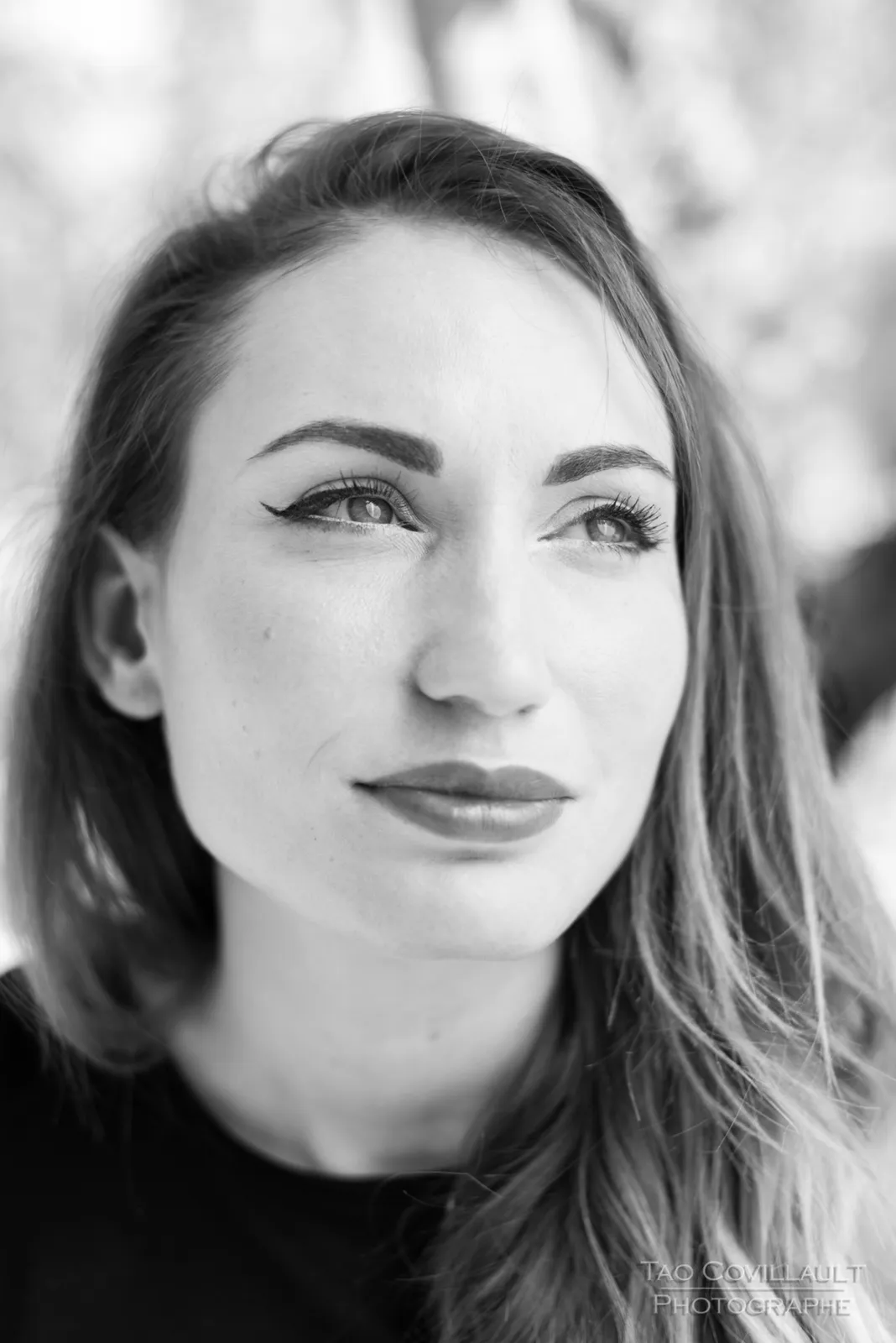 Black-and-white photograph: close-up portrait of a red-haired woman outdoors.