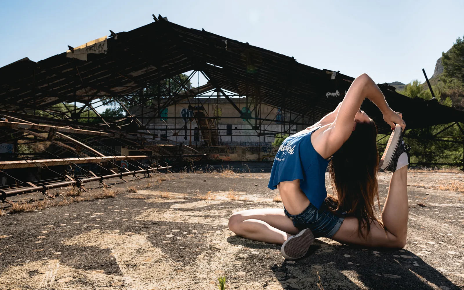 Acrobat bending backward on an industrial rooftop.