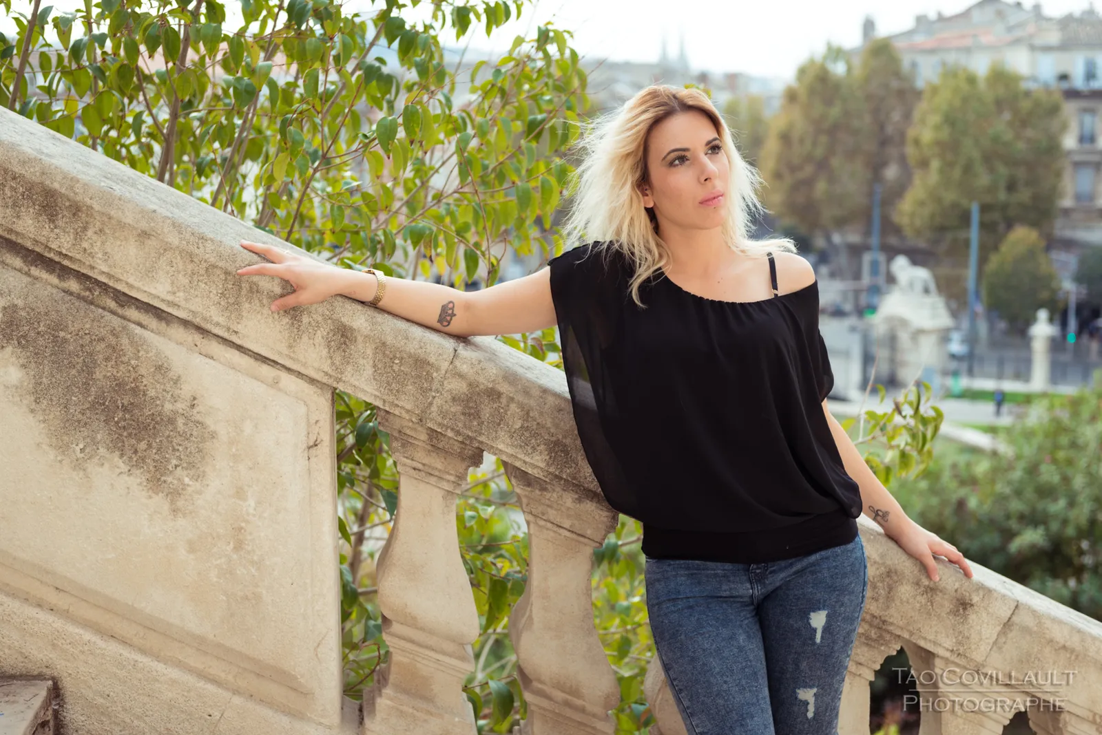Woman in a black top and jeans posing on a stone terrace and steps.