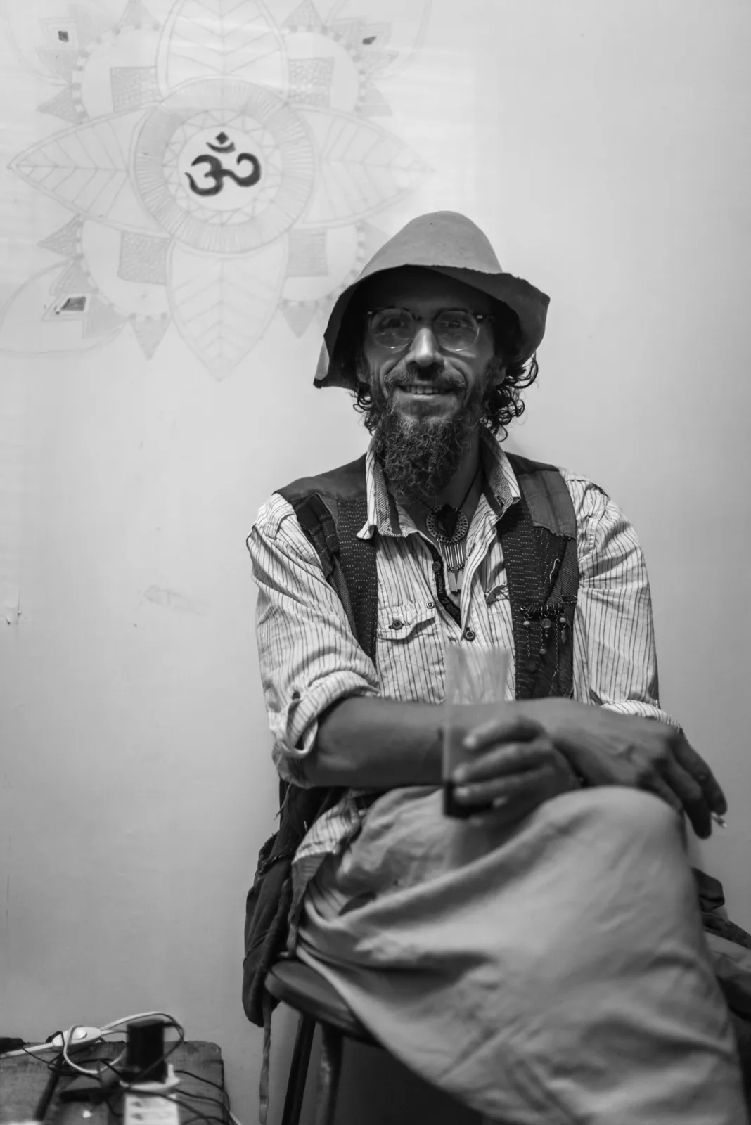 Black-and-white photograph: older man seated against a wall.