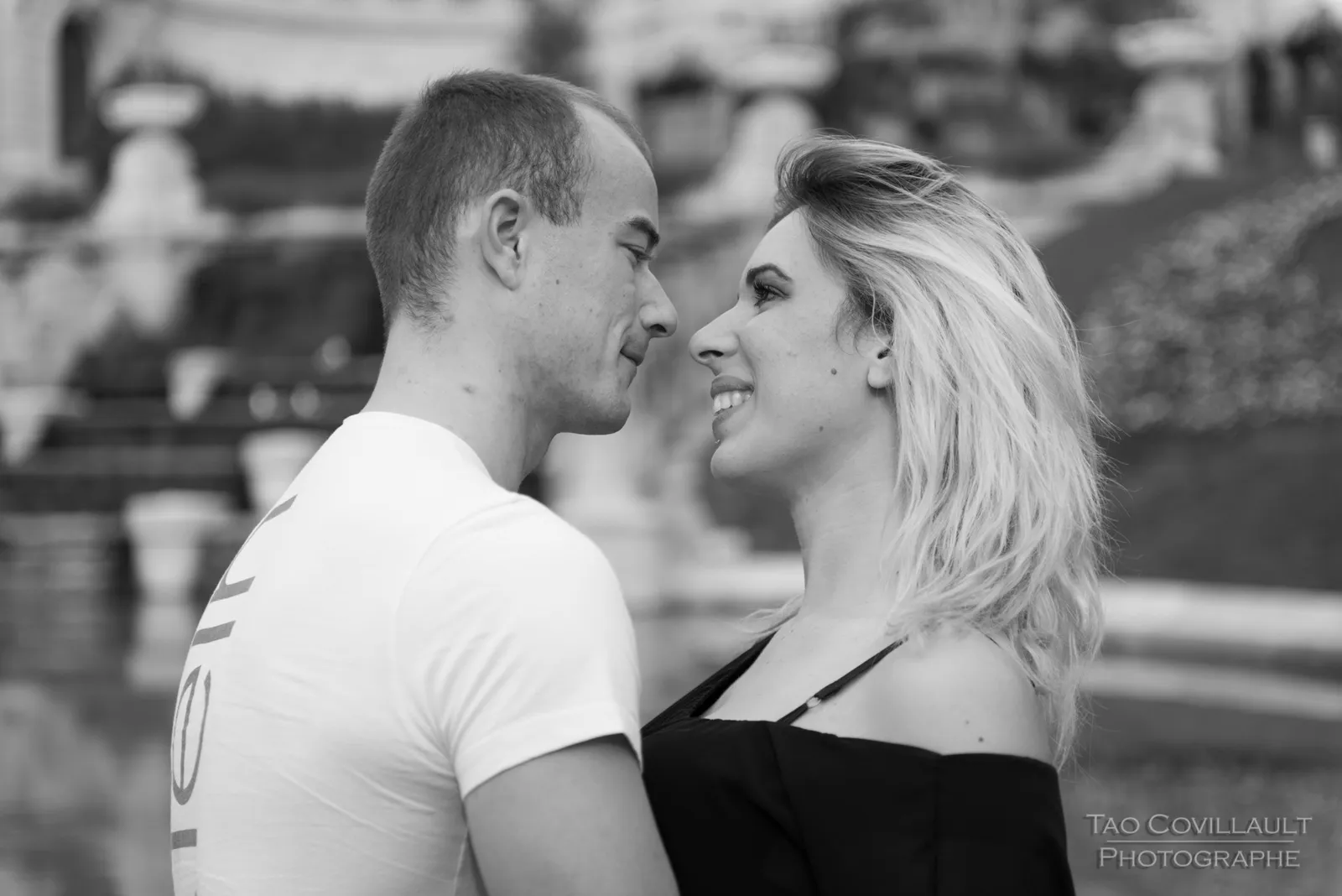 Black-and-white photograph: couple standing together in front of an ornate building.