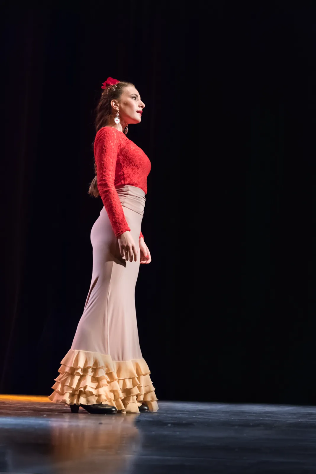 Dancer in a red top and long skirt under stage lights.