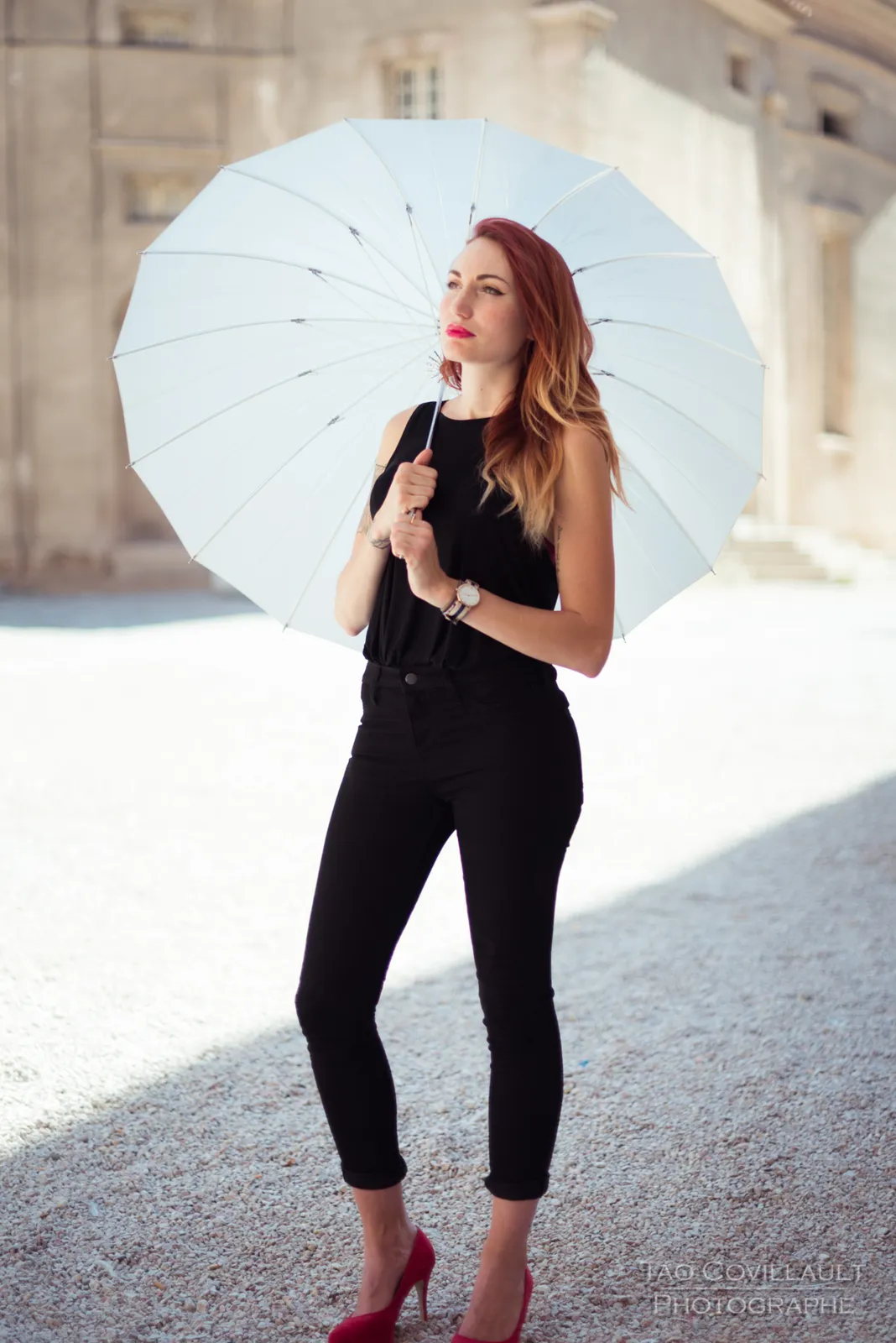 Woman in black clothing holding a white parasol.