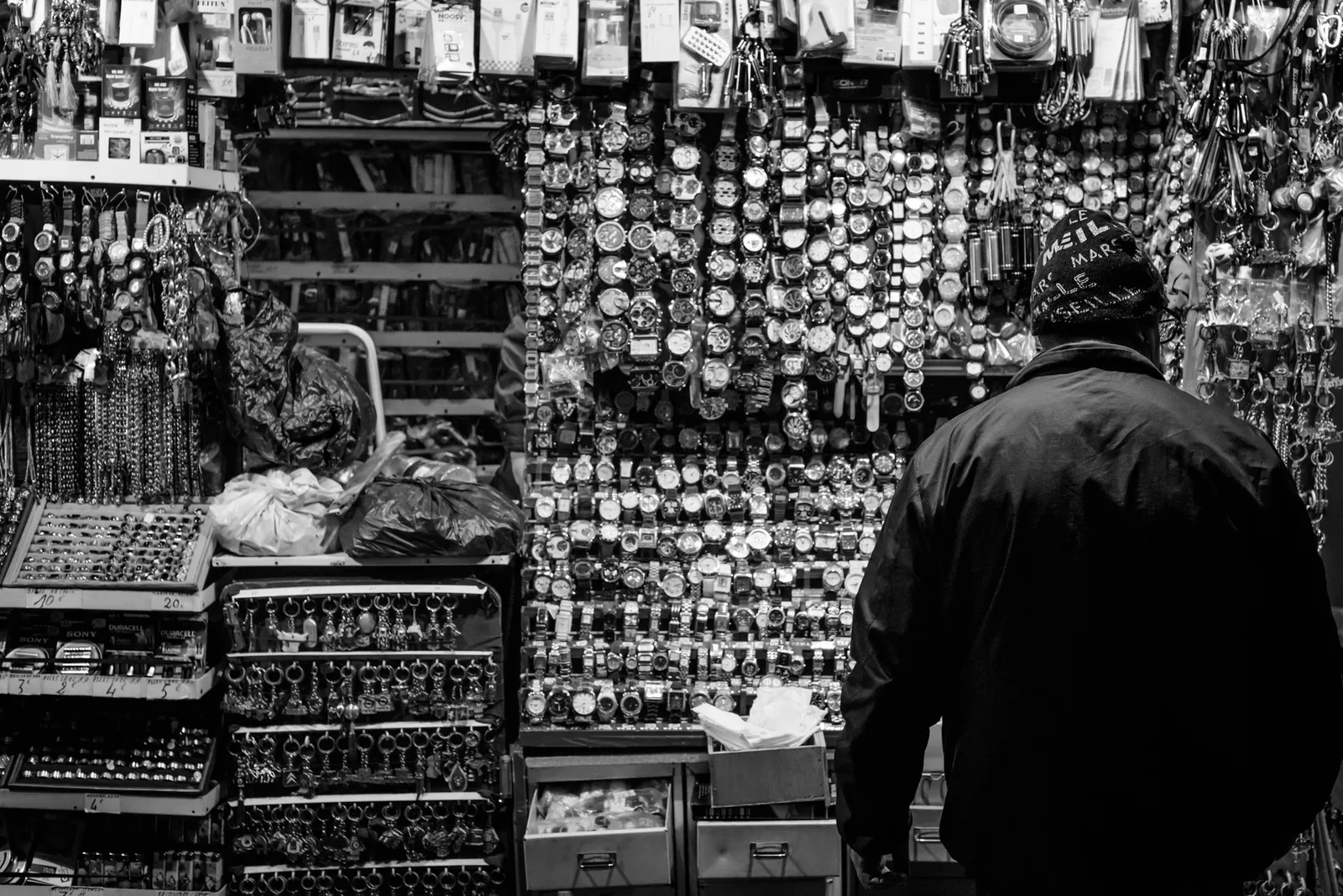 Shopper facing a densely stocked market stall in black and white