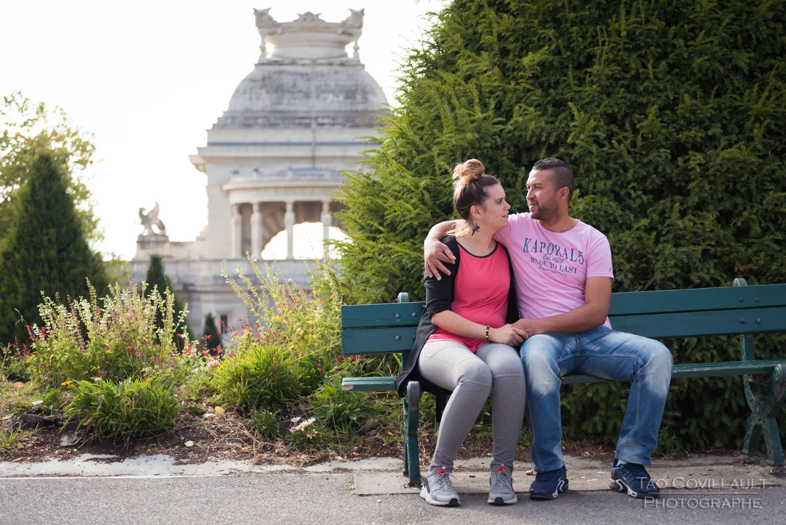 Couple seated together on a green park bench.