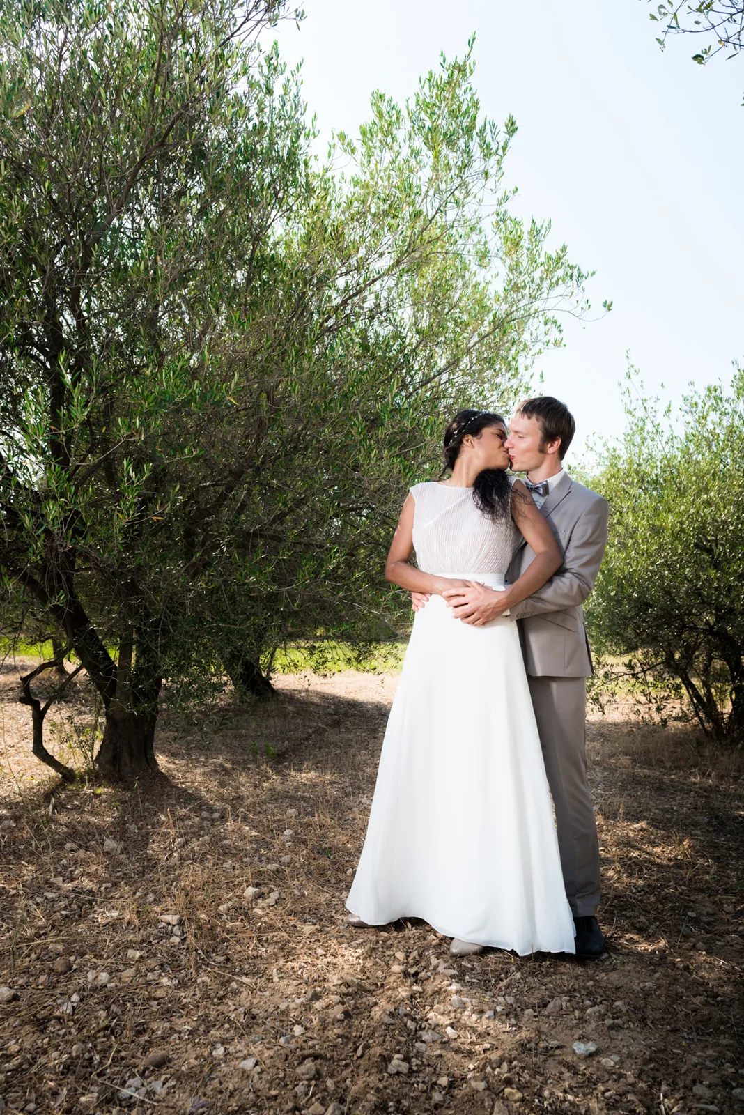 Couple embracing beneath trees.