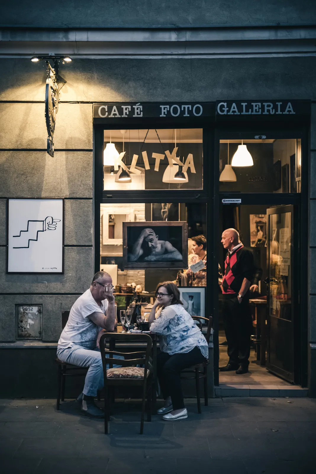 People seated outside a softly lit cafe entrance