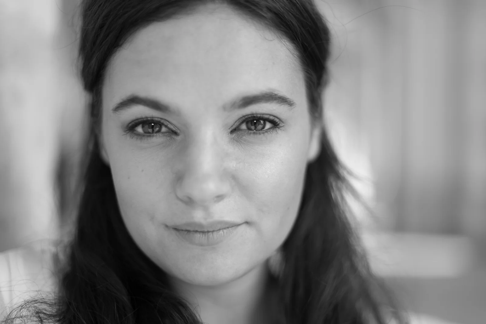 Black-and-white photograph: portrait of a woman in a white dress beside a stone column.