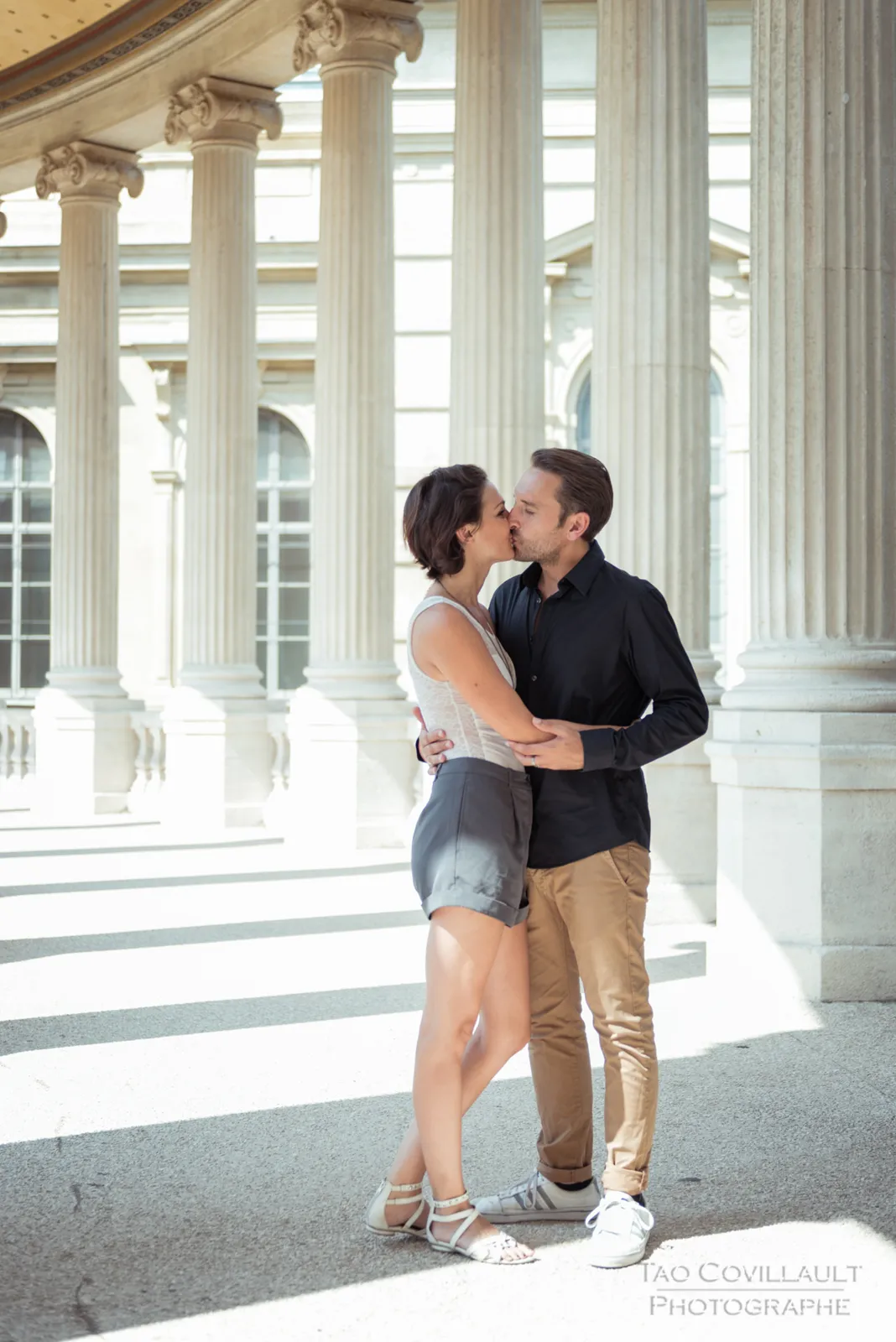 Couple embracing and posing among stone columns.