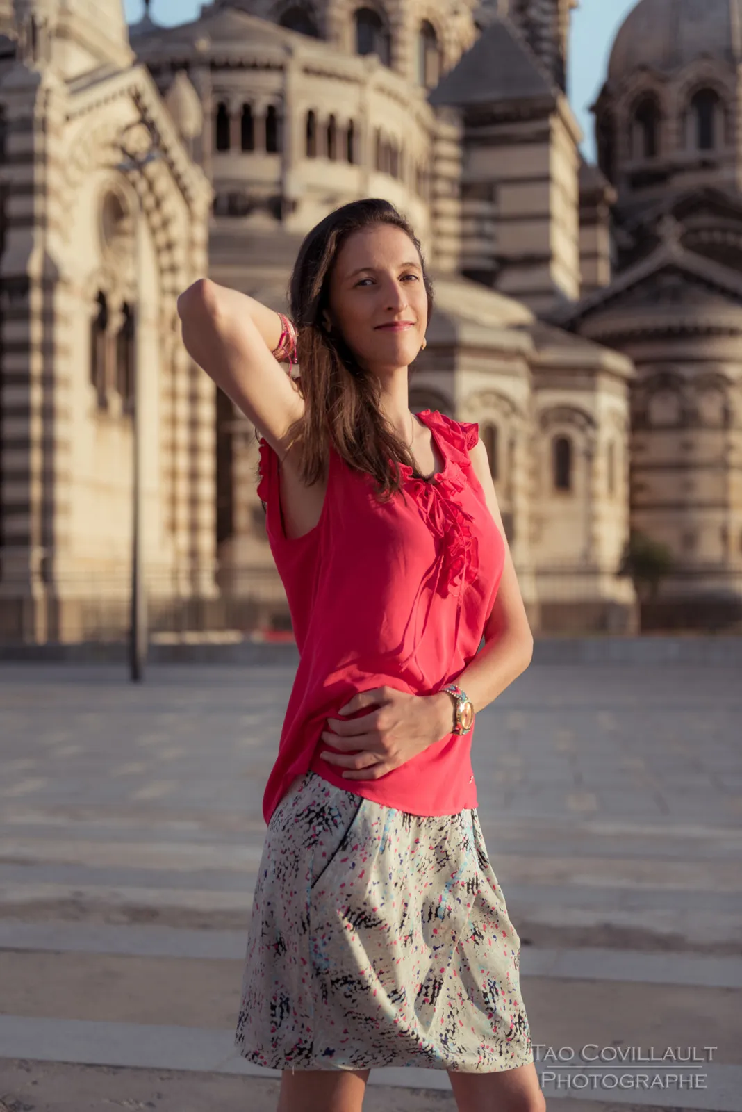 Woman in a bright pink top posing outside an ornate domed stone building.