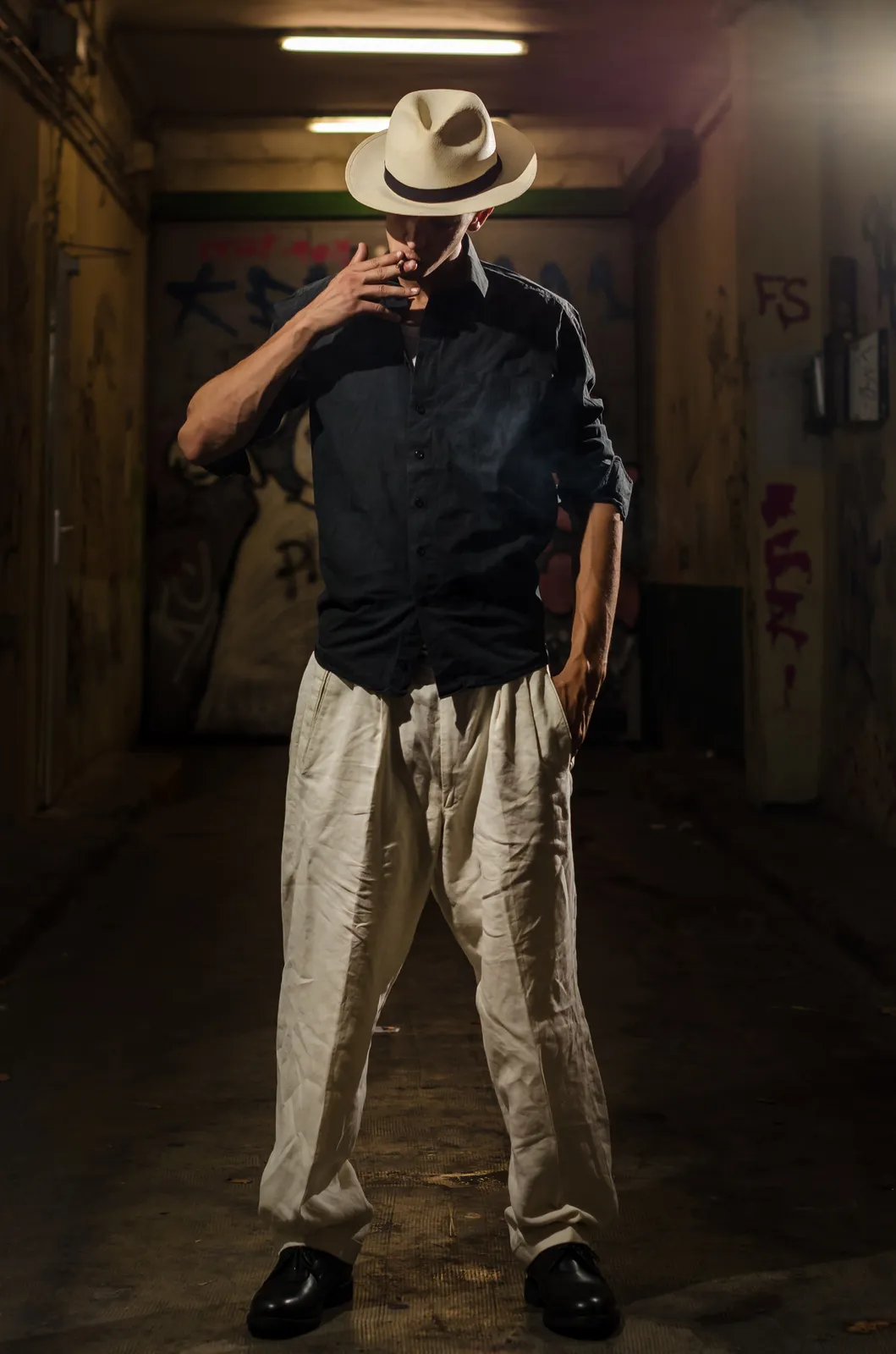 Person in a hat standing under warm corridor lights