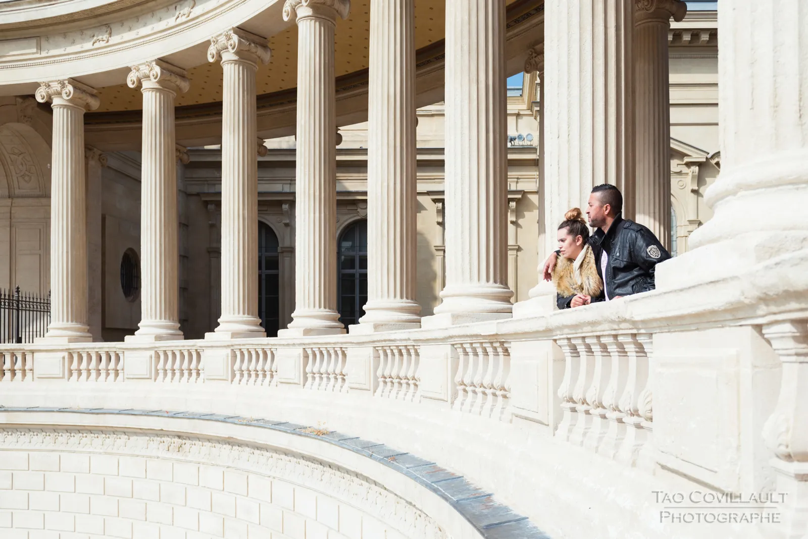Couple posing beside a curved stone balustrade.