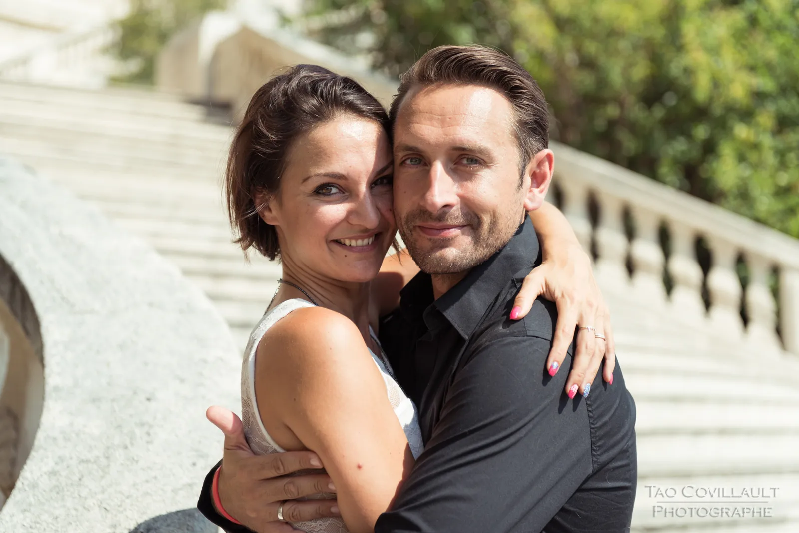 Couple embracing beside a stone balustrade.