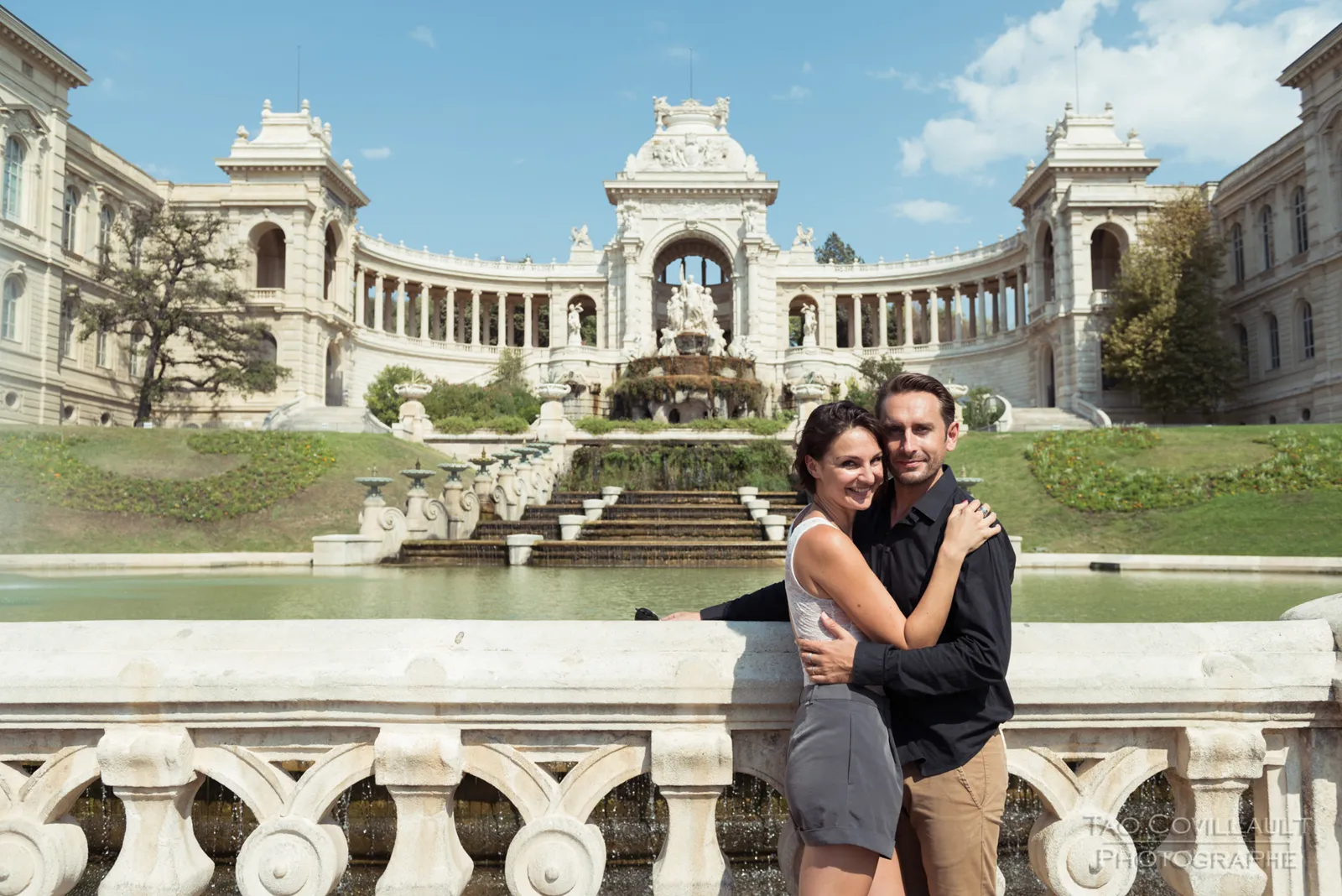Couple seated together on a stone balustrade.