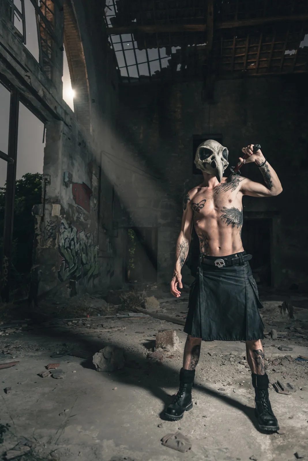 Shirtless figure posing inside a dark abandoned building