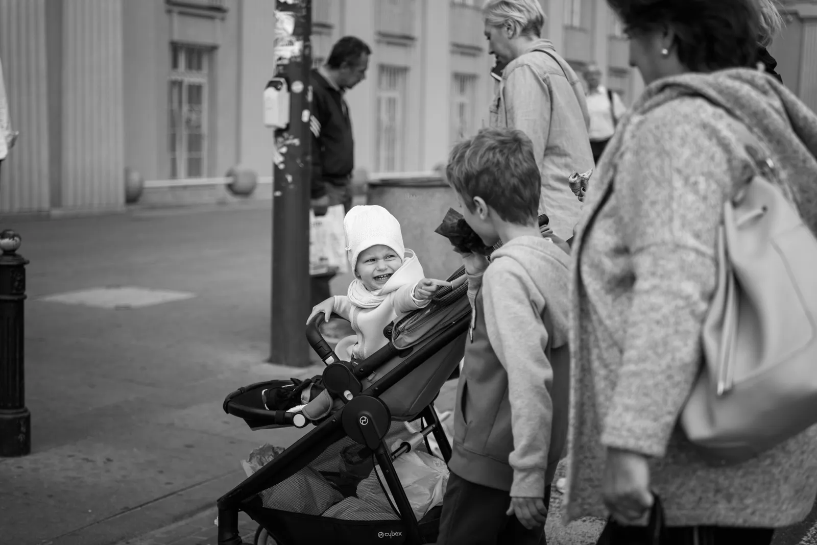 People gathered around a stroller on a city sidewalk