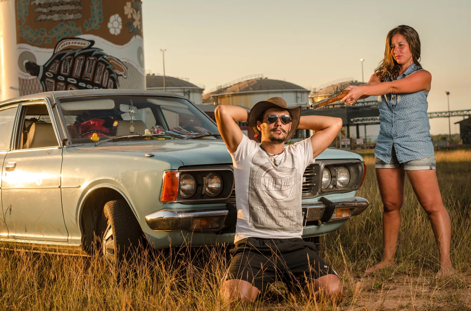 Two people posing beside a vintage car in warm light