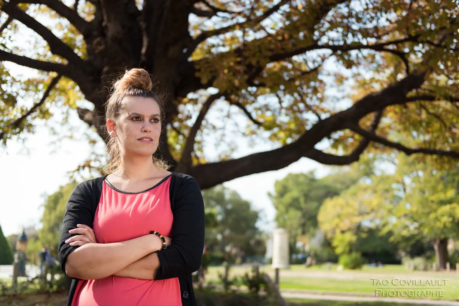 Woman in a pink top standing beneath a tree.