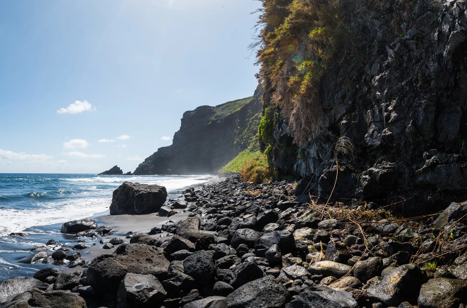 Dark pebble beach beneath steep coastal cliffs