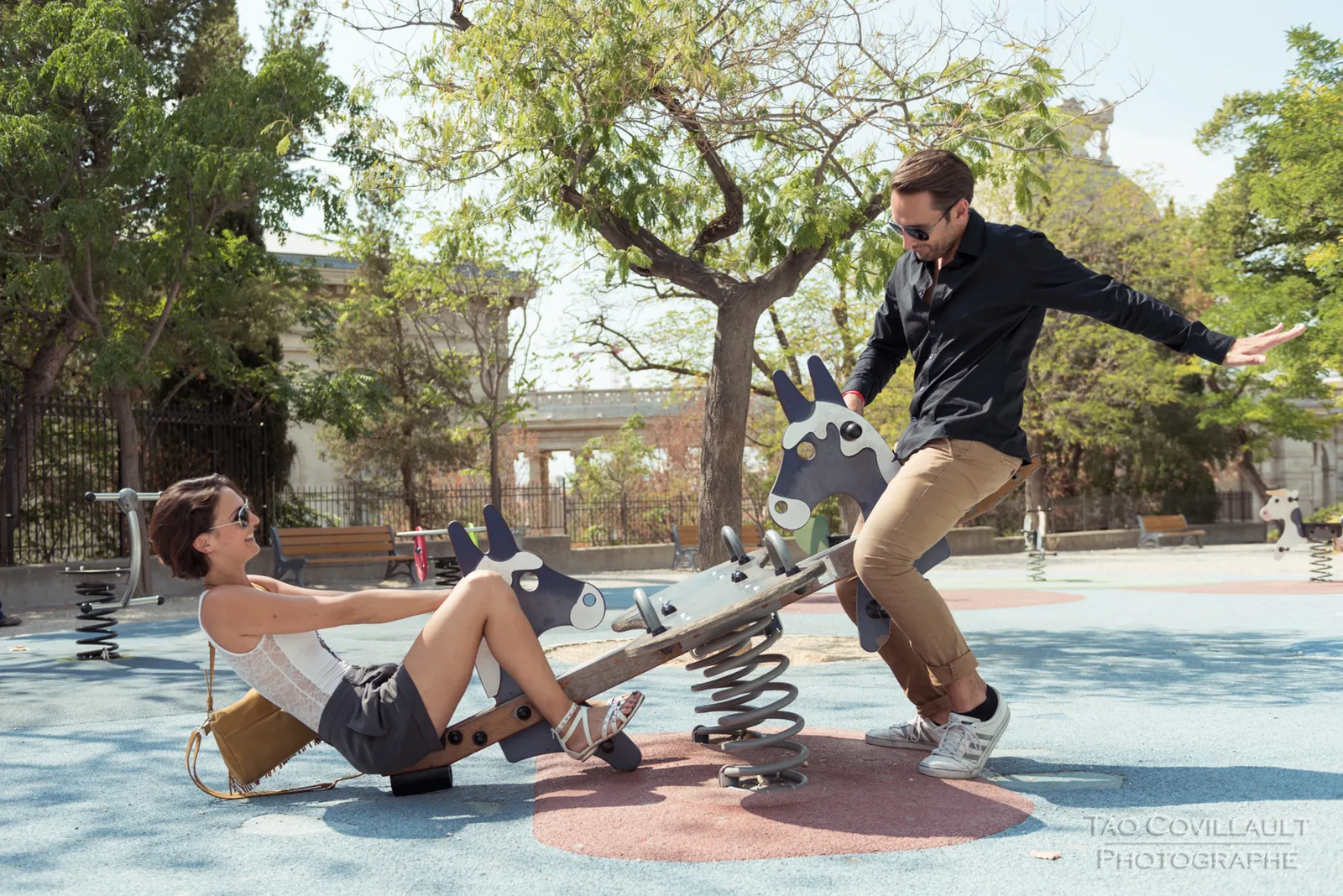 Couple playing on a playground seesaw.