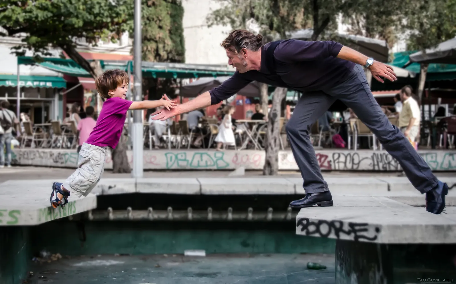 Adult and child reaching toward each other above a canal