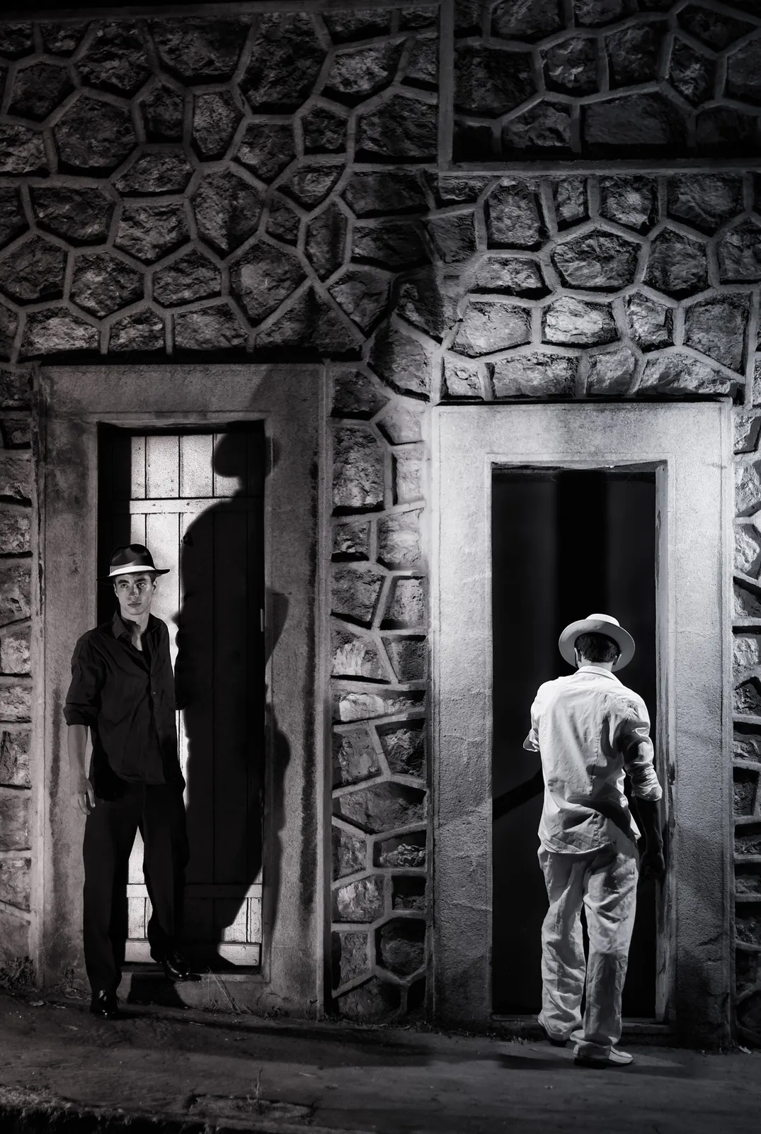 Two figures standing in stone doorways in black and white