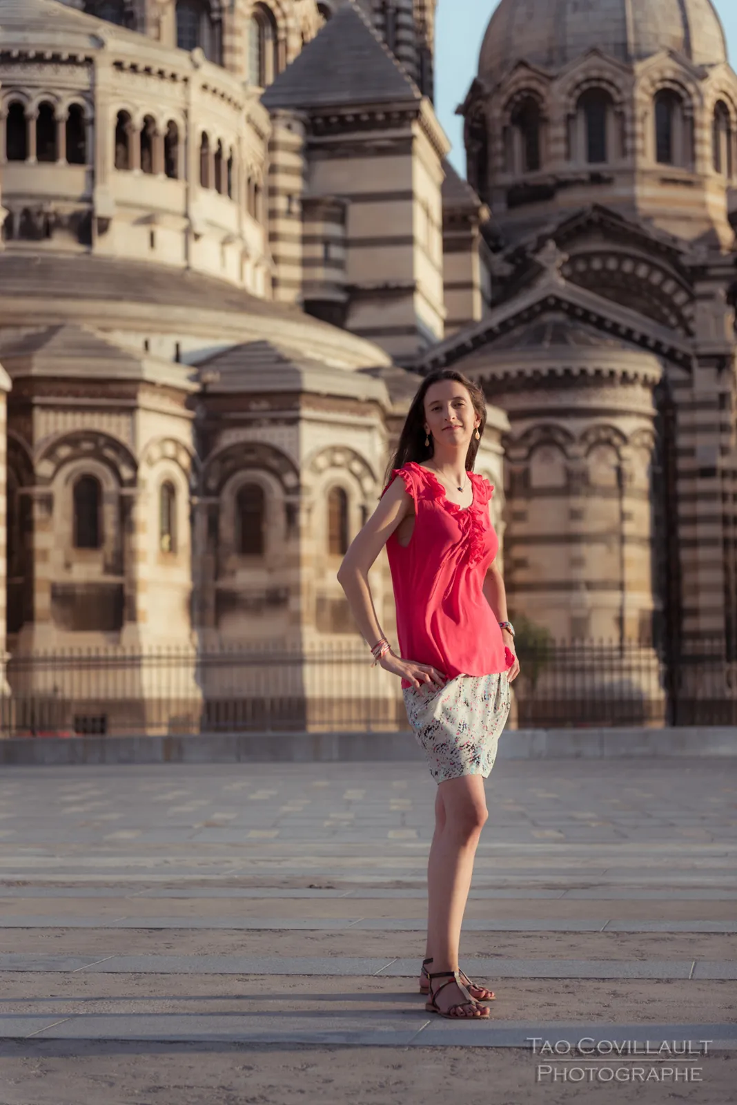 Woman in a bright pink top posing outside an ornate domed stone building.