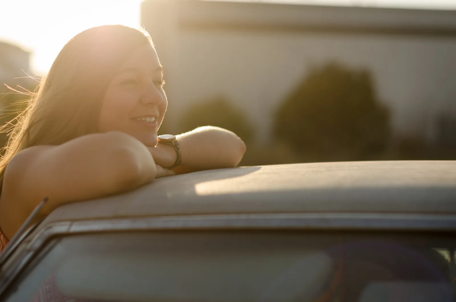 Backlit portrait of a person leaning on a car roof