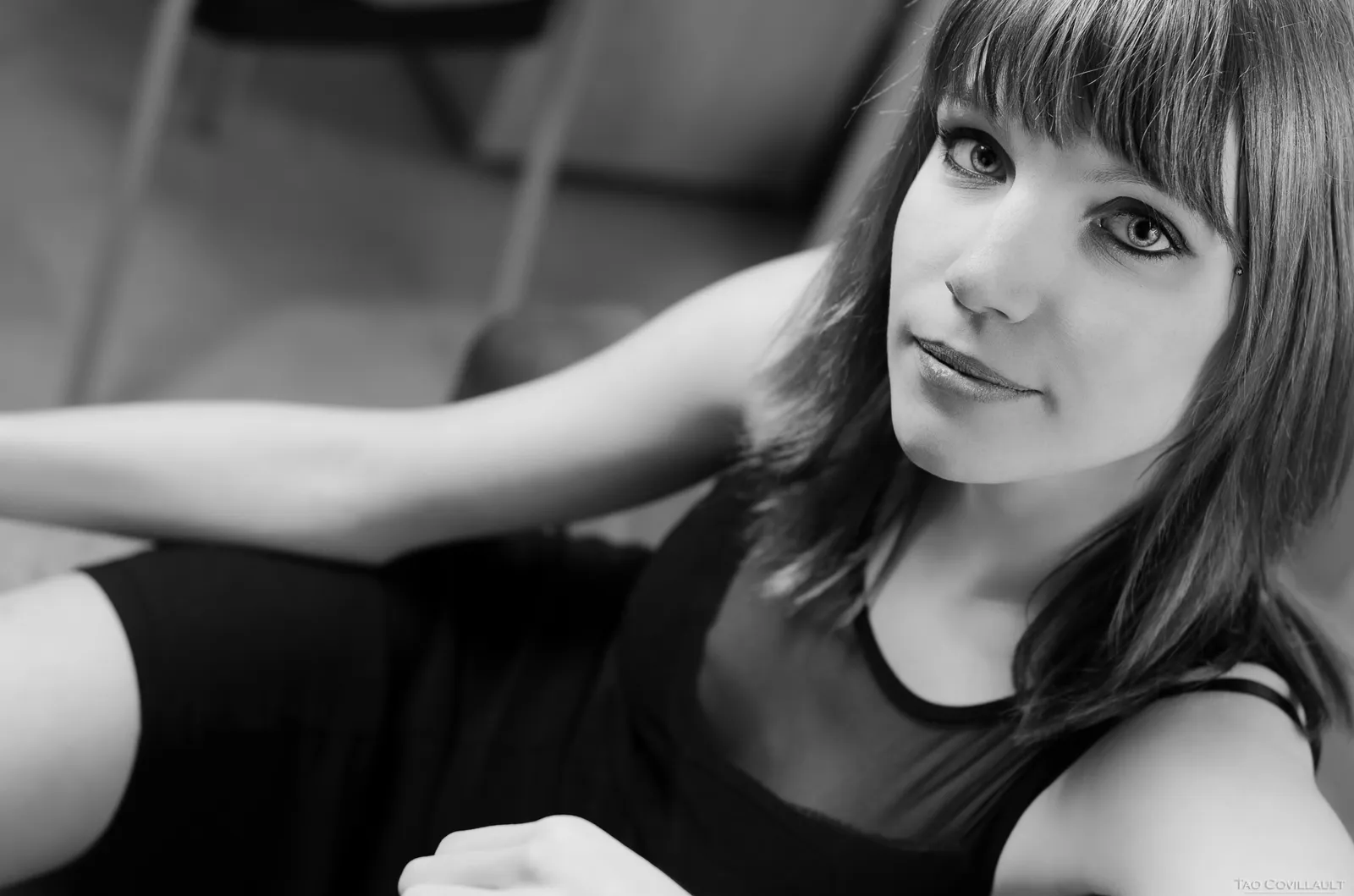 Black-and-white photograph: woman with bangs seated indoors.
