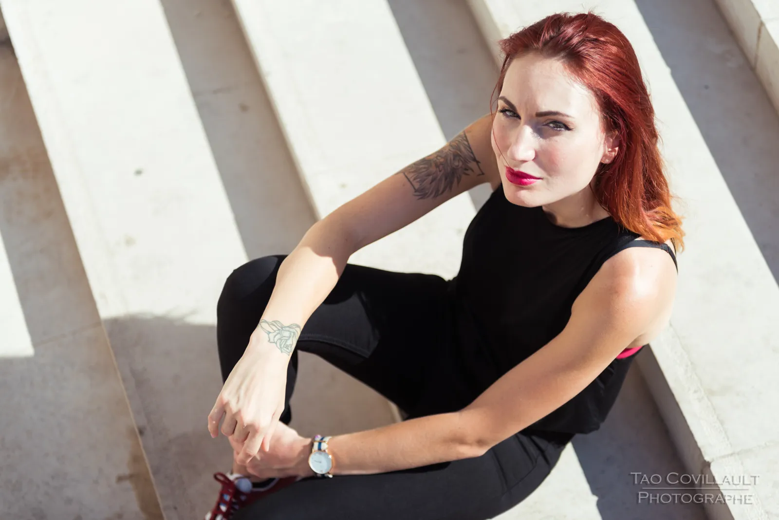 Woman in black clothing posing on pale stone steps.