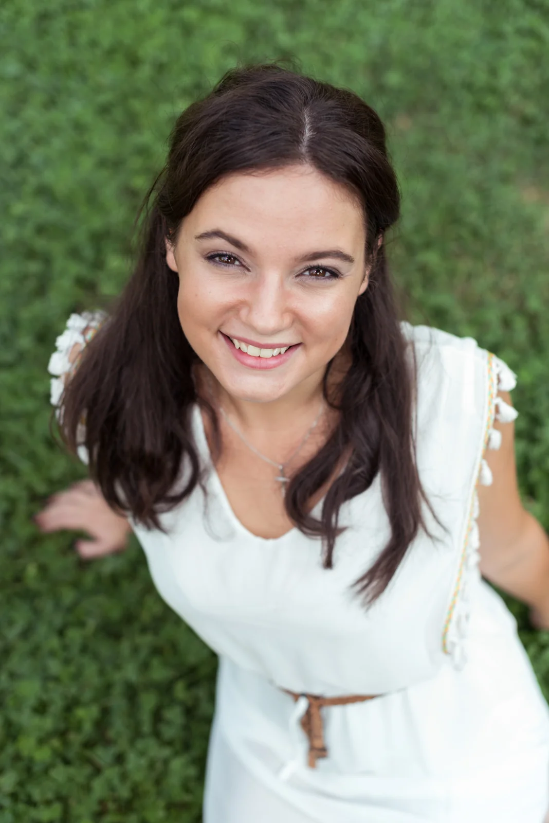 Woman in a white dress relaxing on grass.