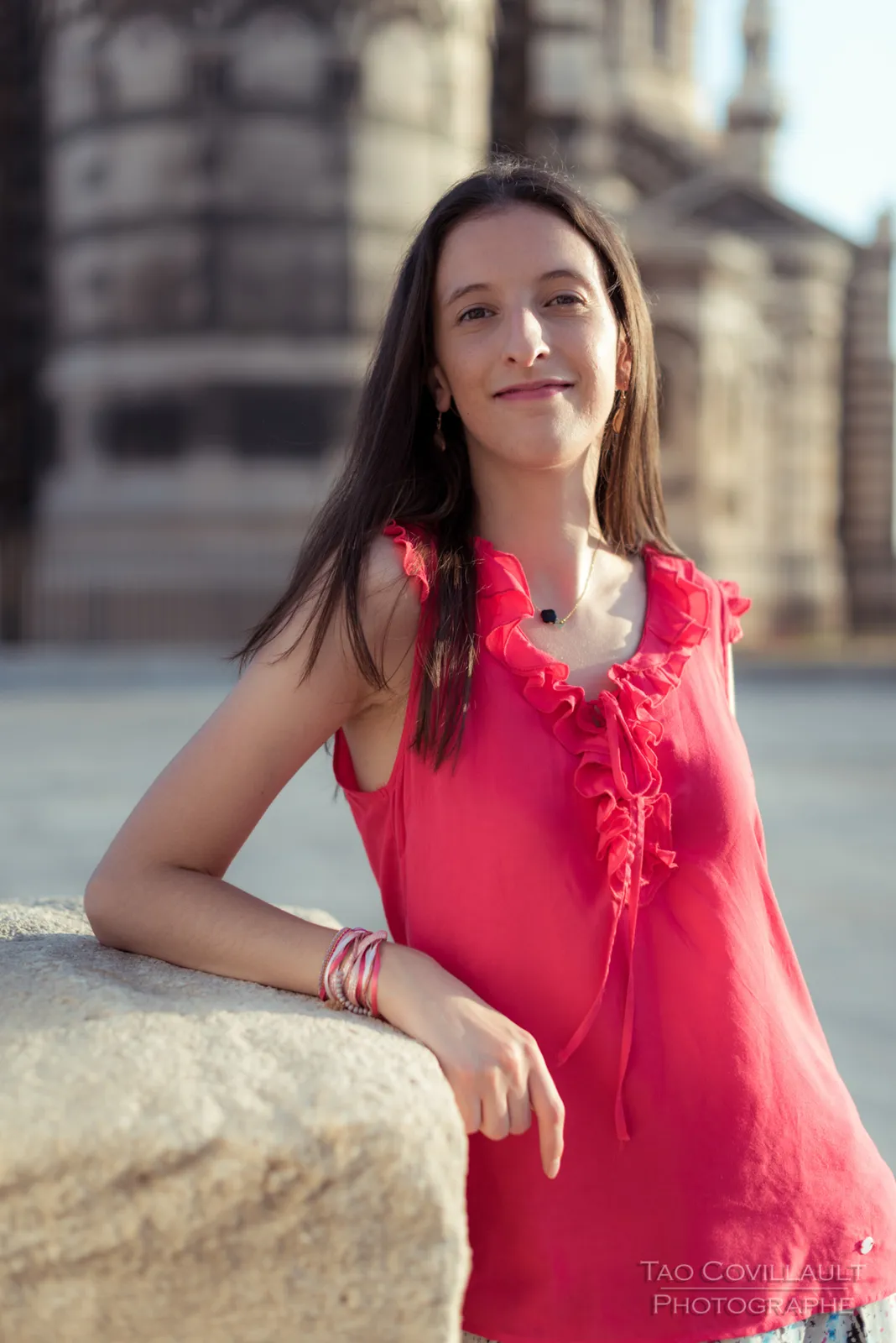 Woman in a bright pink top posing outside an ornate domed stone building.