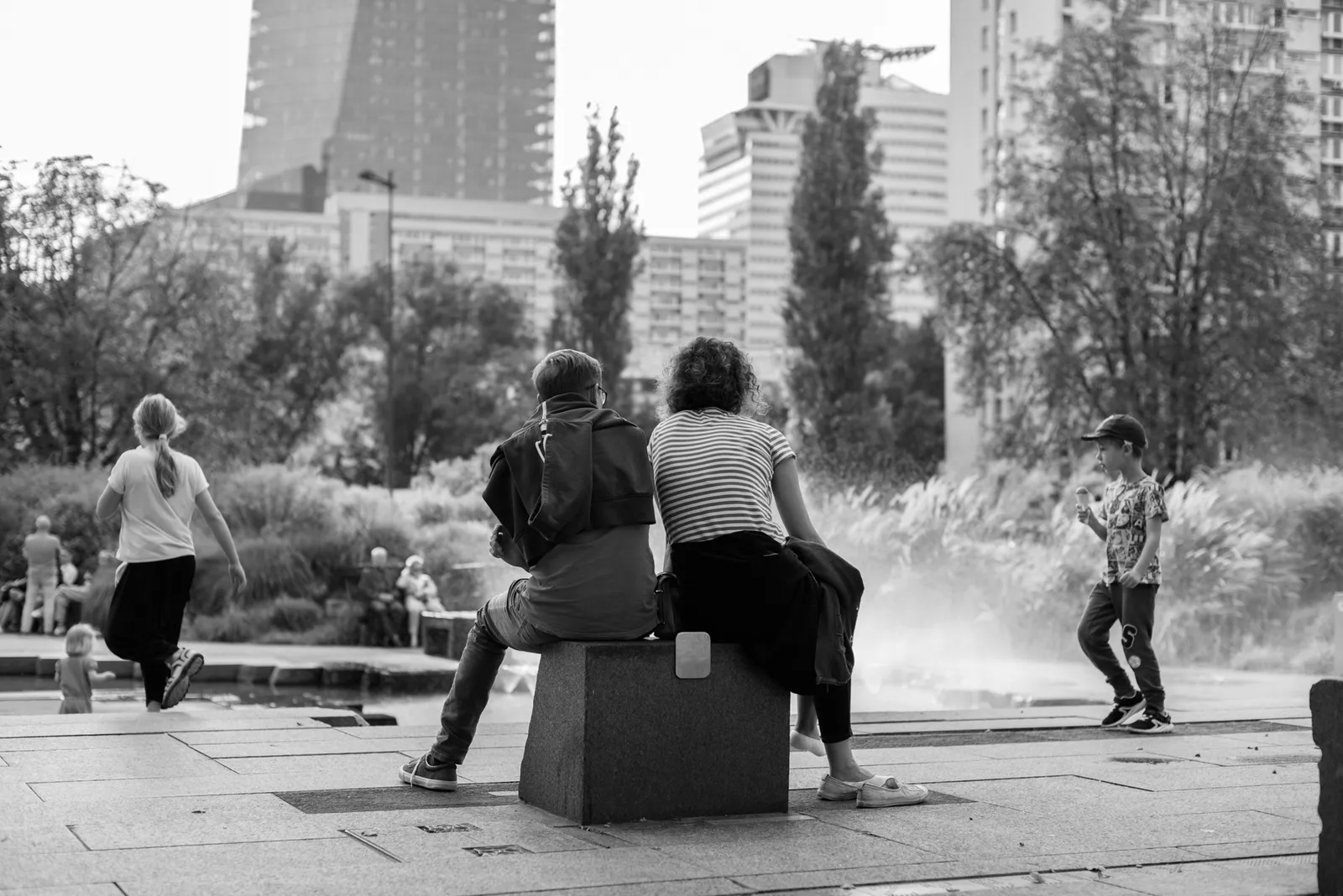 People sitting and walking in a city park in black and white