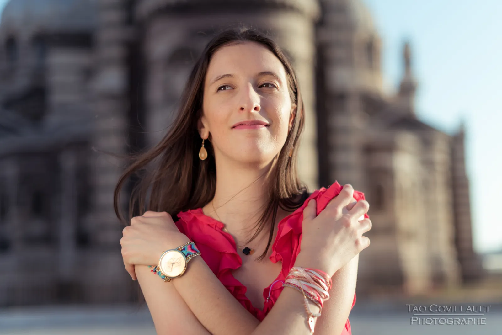 Woman in a bright pink top posing outside an ornate domed stone building.