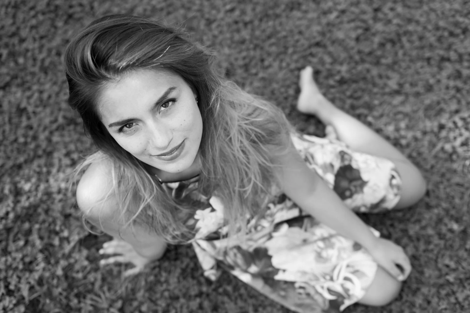 Black-and-white photograph: portrait of a woman in a floral dress outdoors.