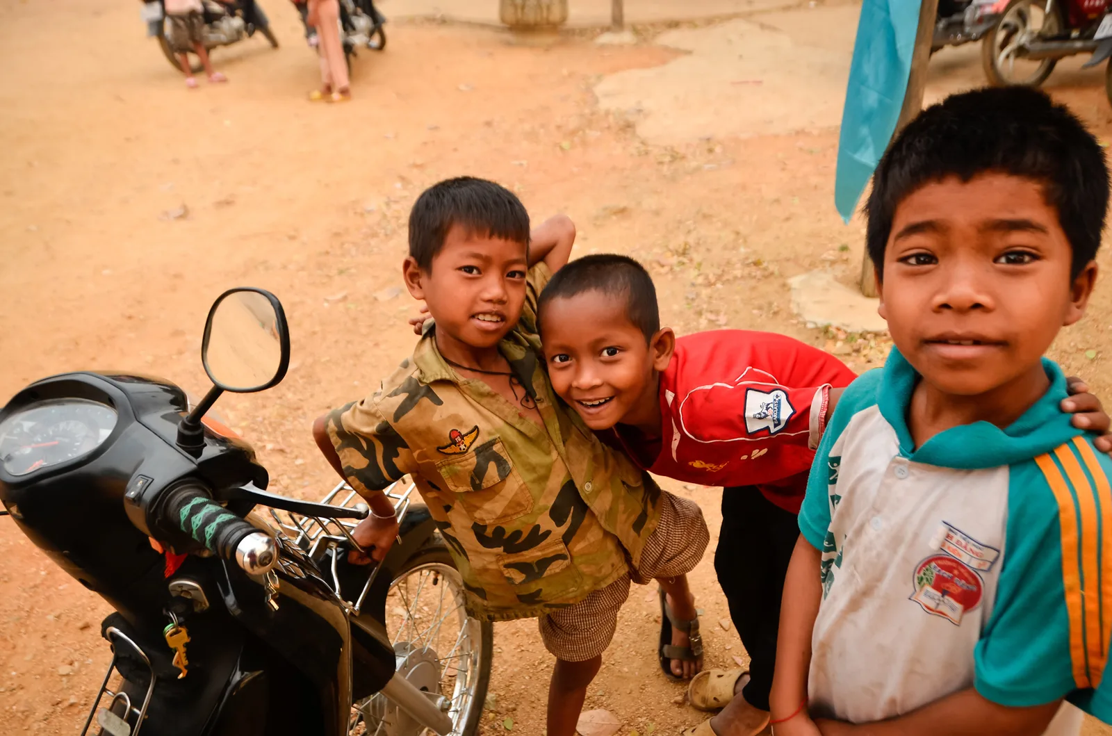 Three children gathered beside a motorbike.