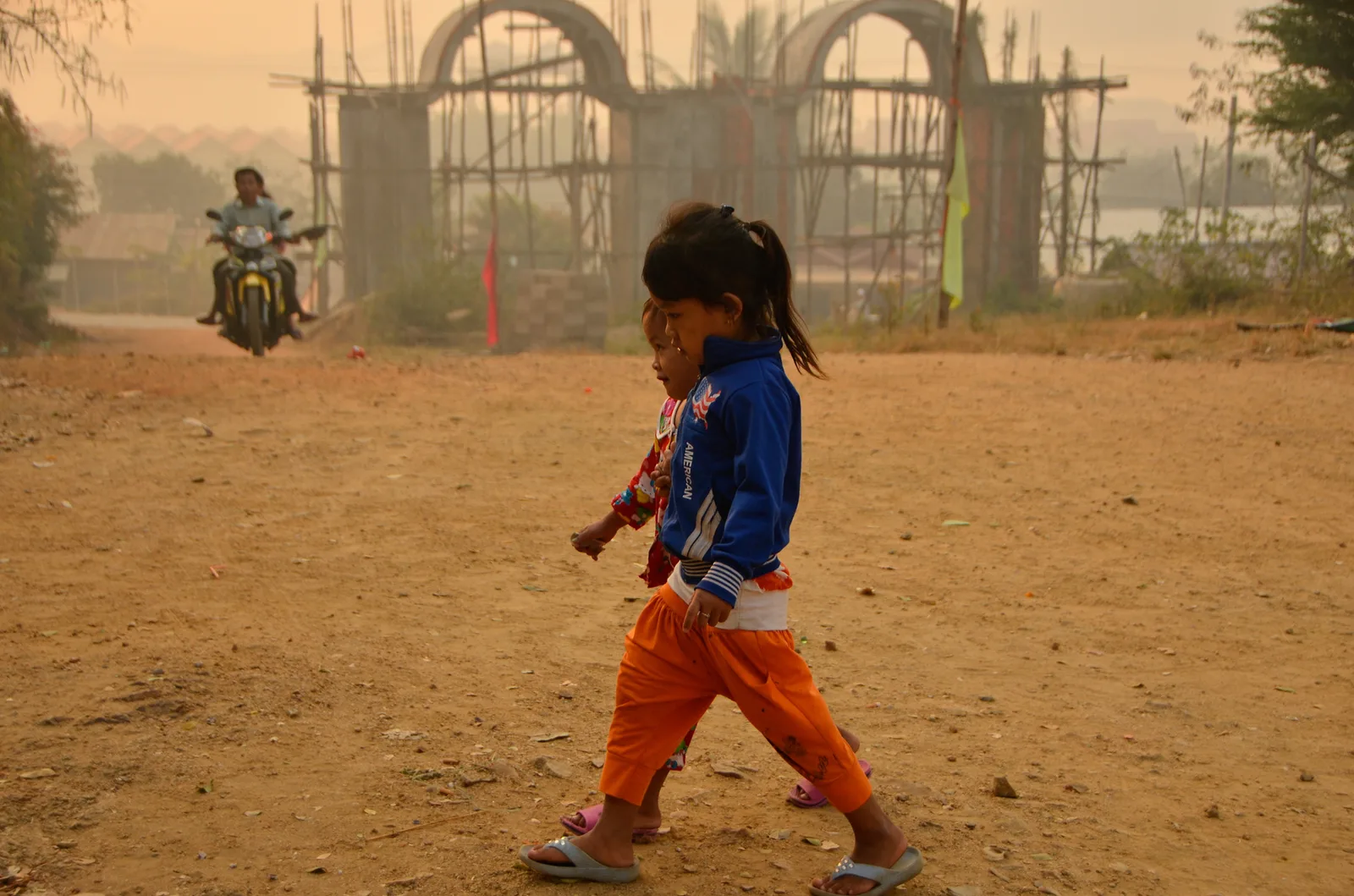 Child walking across a dusty temple courtyard.