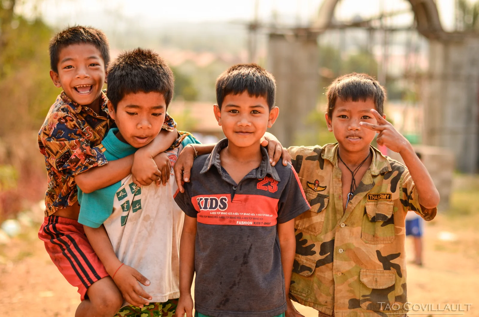 Four smiling children standing with their arms around each other.