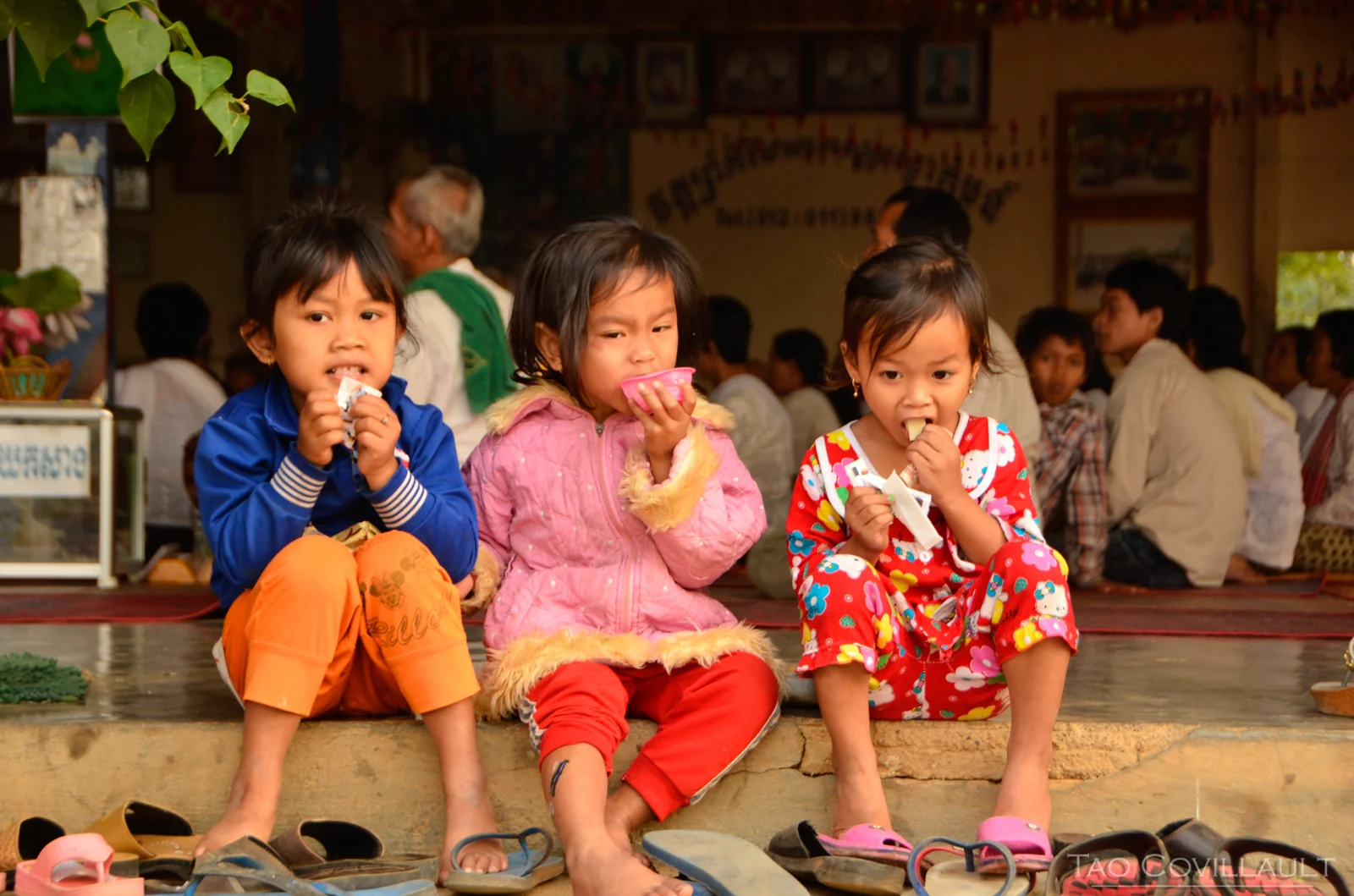 Three children eating while seated on a temple step.