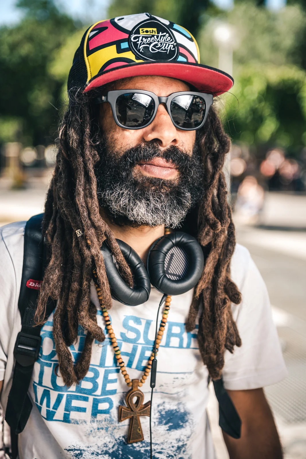 Portrait of a bearded man with dreadlocks, sunglasses and headphones.