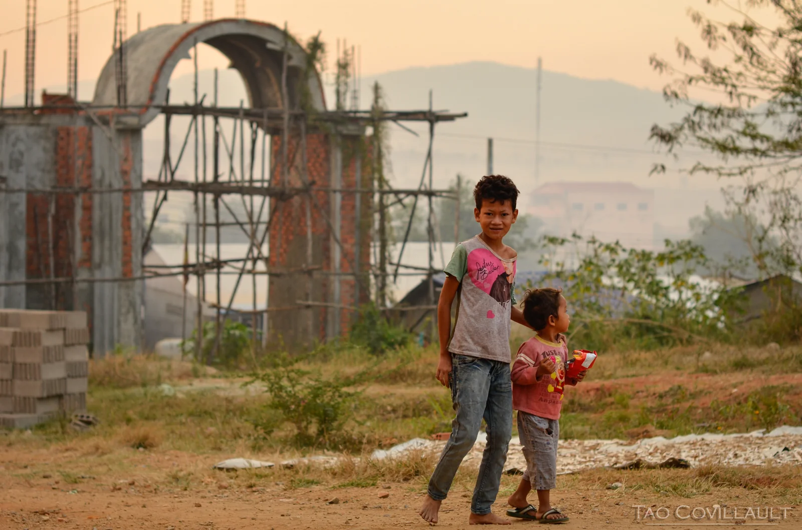 Two children standing outside a temple under construction in Cambodia.