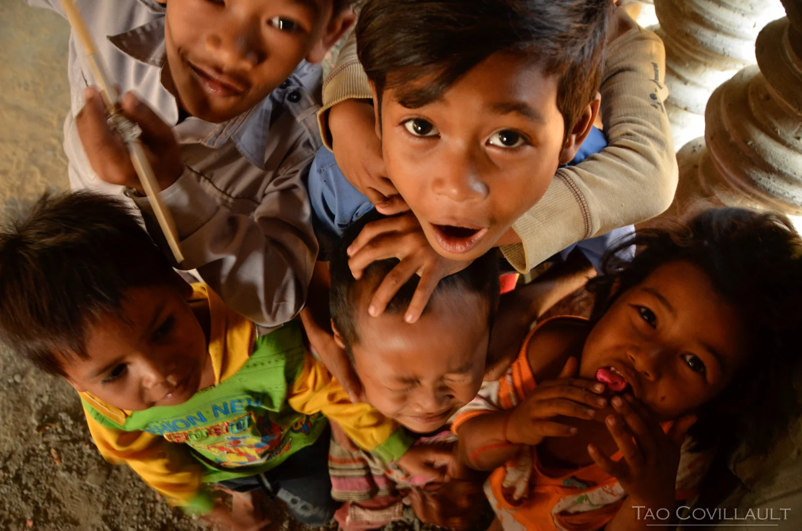 Group of children crowding together and looking up at the camera.