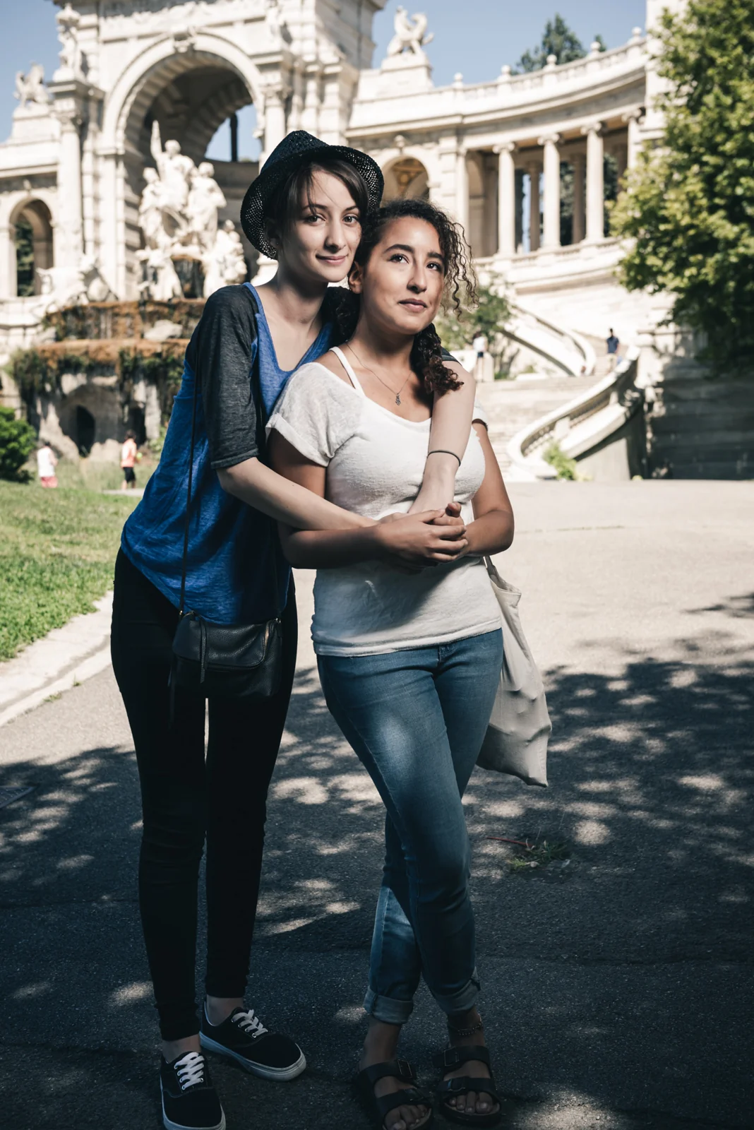 Two people embracing in front of a monumental fountain.