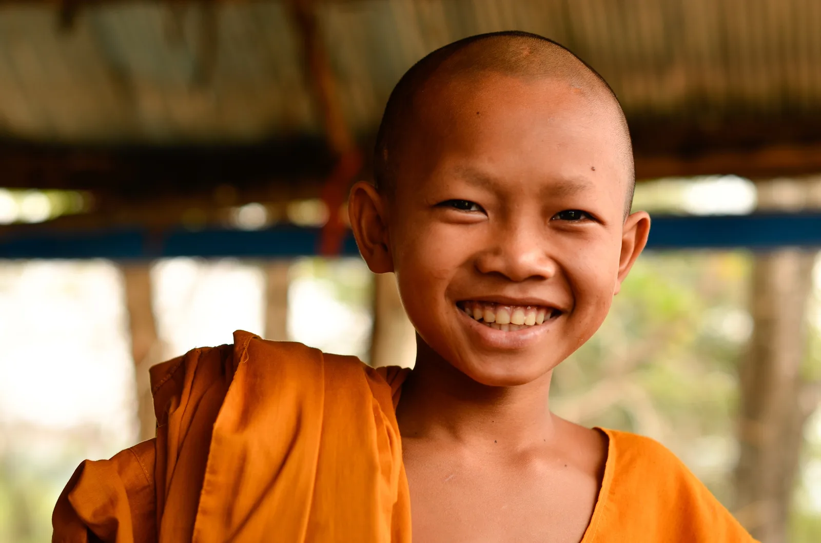 Smiling young monk wearing an orange robe.