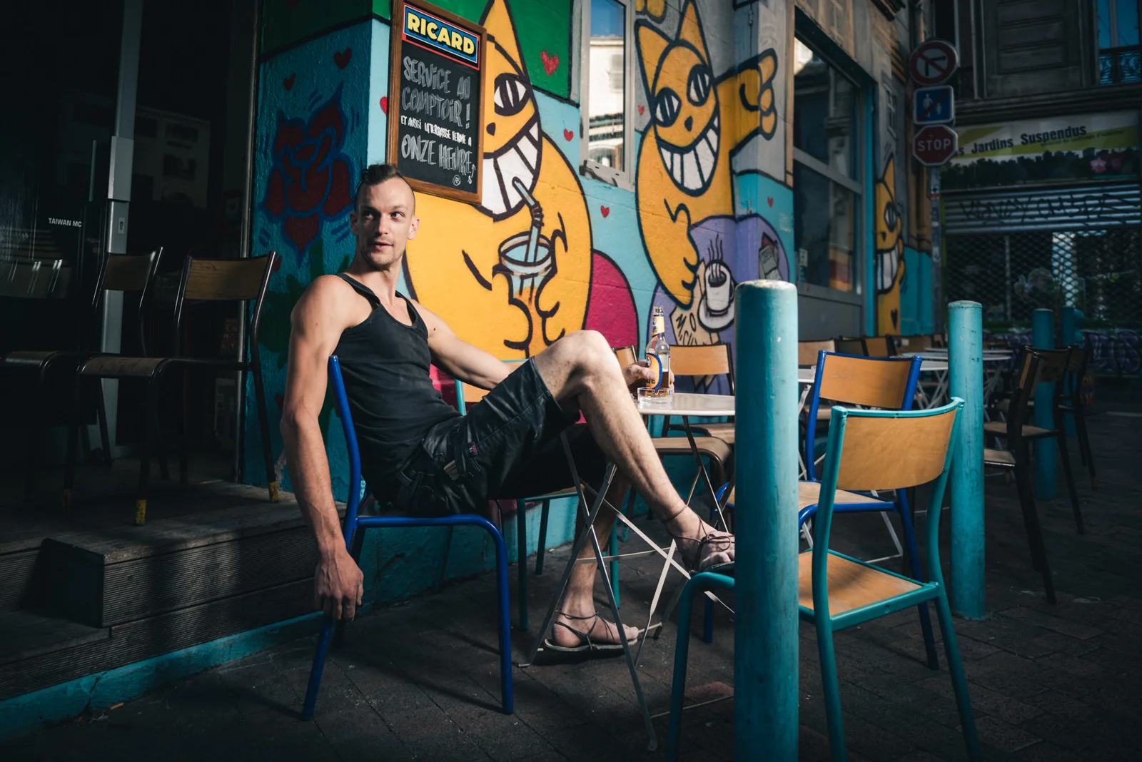 Person seated among colorful chairs outside a café.
